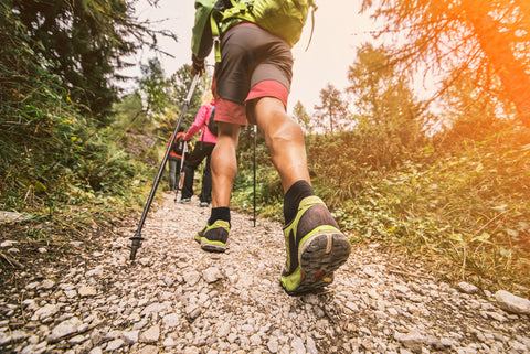 A hiker makes their way down trail, with the help of their hiking poles and other adventure gear.